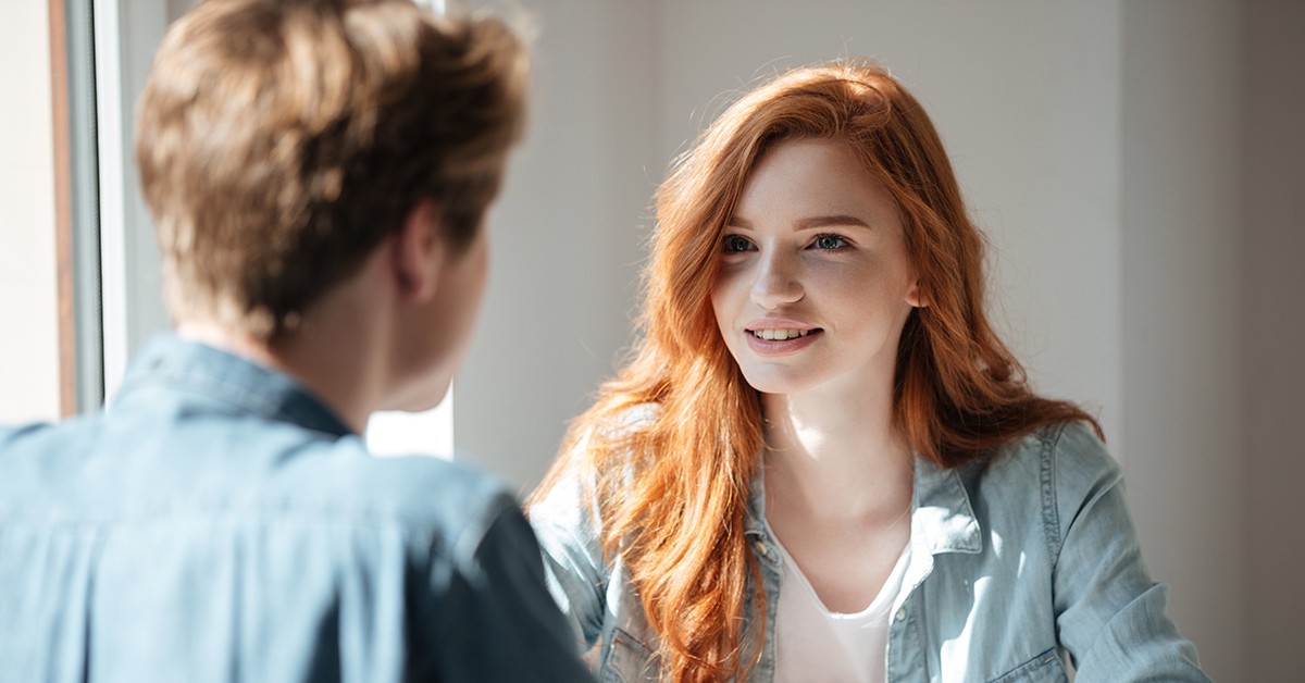 Een foto van een gesprek tussen twee mensen: ene persoon van vanachter, de andere persoon kijkt naar die persoon