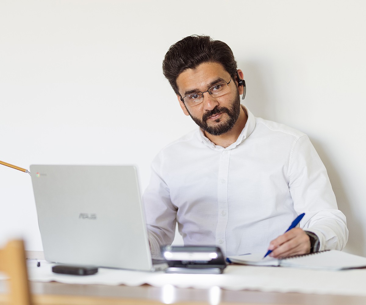 Een foto van een persoon die voor laptop zit